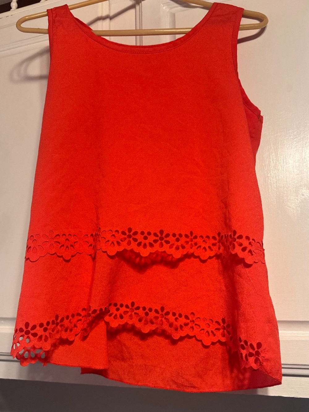 Bright red sleeveless top with decorative eyelet tiers. Soft, structured fabric
